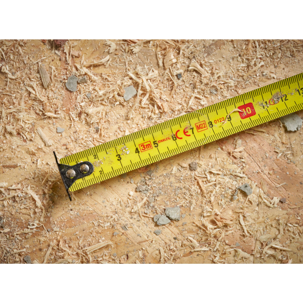 Mètre ruban Stanley, outil de mesure jaune, utilisé sur des copeaux de bois.