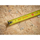 Mètre ruban Stanley, outil de mesure jaune, utilisé sur des copeaux de bois.