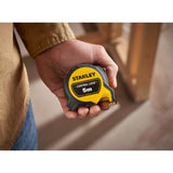 Stanley mètre ruban jaune et noir, outil de mesure 5m, tenu en main.