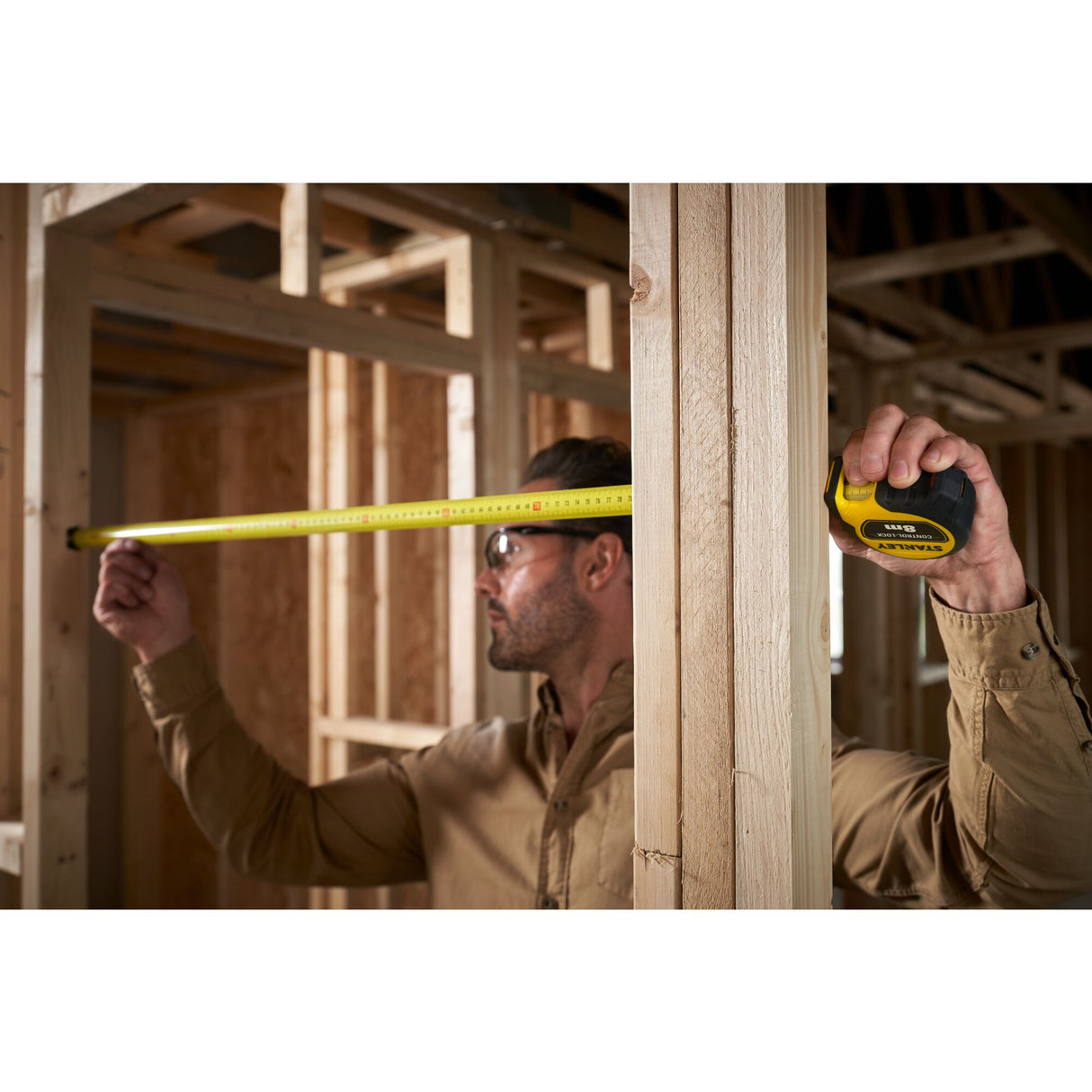 Mètre ruban Stanley, outil de mesure jaune, utilisé sur un chantier de construction bois