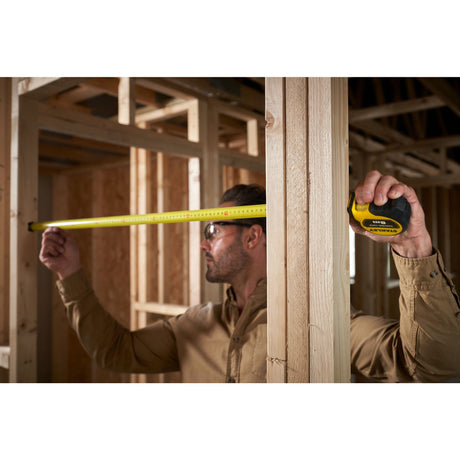 Mètre ruban Stanley, outil de mesure jaune, utilisé sur un chantier de construction bois