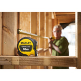 Mètre ruban Stanley jaune et noir, 10m, outil de mesure, utilisé sur un chantier bois