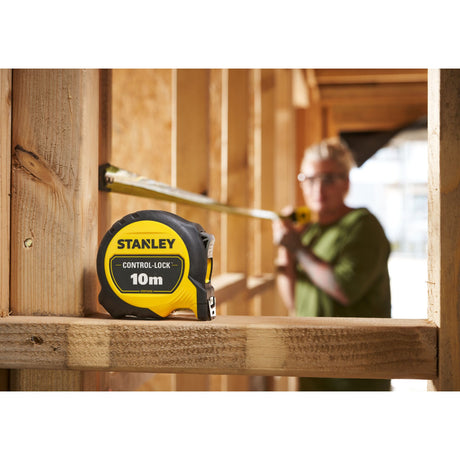 Mètre ruban Stanley jaune et noir, 10m, outil de mesure, utilisé sur un chantier bois