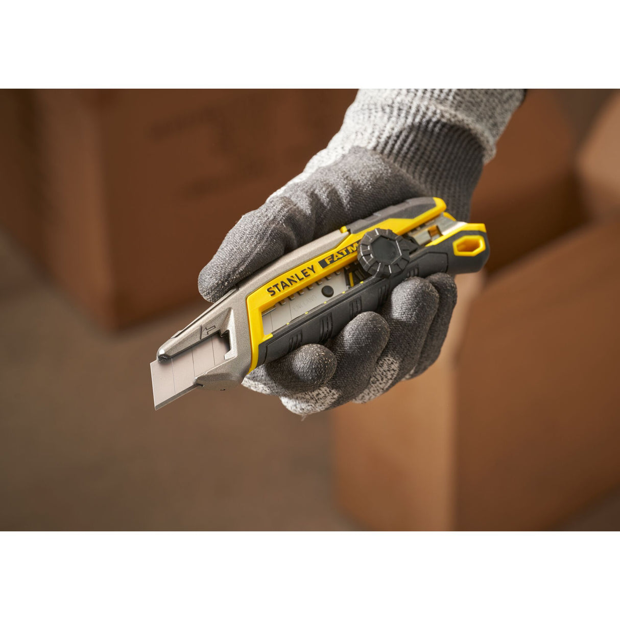 Cutter Stanley, outil de découpe, couleur gris et jaune, tenu en main gantée