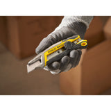 Cutter Stanley, outil de découpe, couleur gris et jaune, tenu en main gantée