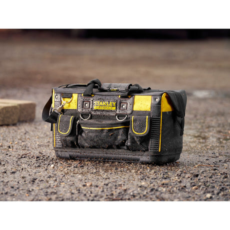 Sac à outils Stanley Fatmax, type sacoche, noir et jaune, posé sur sol humide