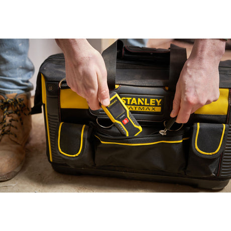 Télémètre laser Stanley noir et jaune rangé dans une sacoche d’outils, outil de mesure professionnel.