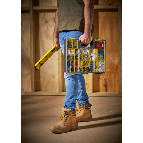 Boîte de rangement Stanley, type organiseur, couleur jaune, tenue par un homme en chantier.