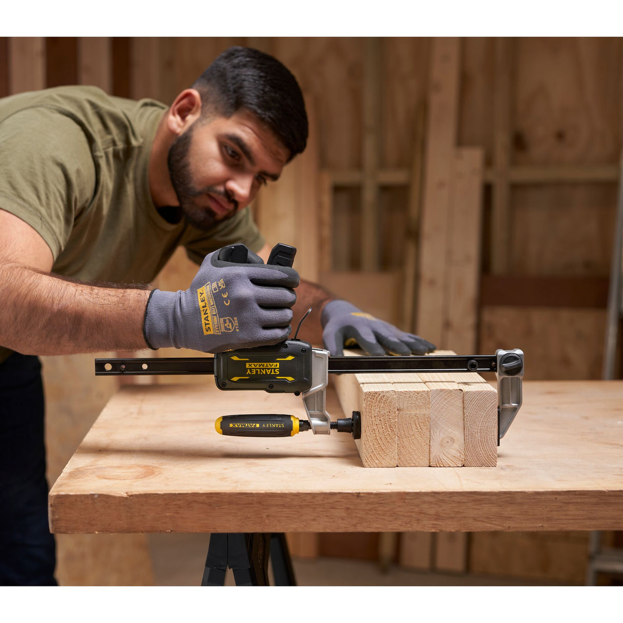Serre-joint Stanley jaune et noir utilisé pour serrer des planches de bois sur un établi