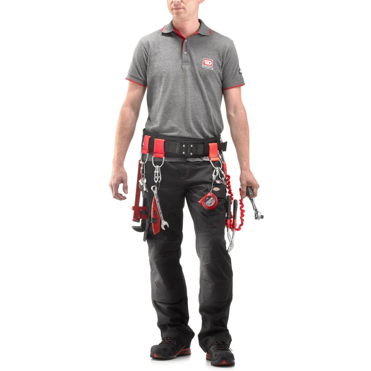 Homme portant une ceinture porte-outils Facom noire et rouge avec outils, pantalon noir, polo gris.