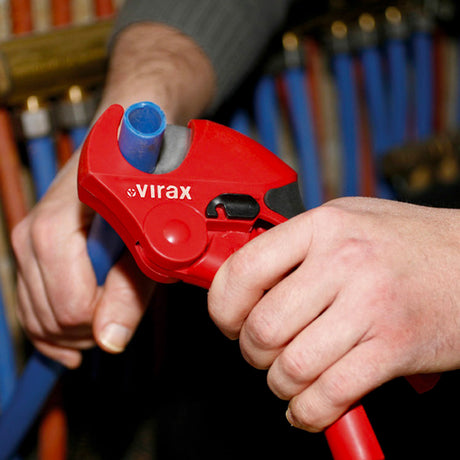 Coupe-tube rouge Virax pour plomberie utilisé sur un tube bleu