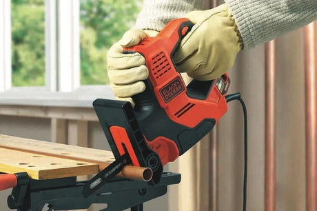 Scie électrique Black+Decker, outil électroportatif rouge et noir, en action sur tube cuivre.