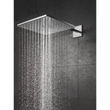 Pommeau de douche Grohe, modèle carré, couleur chromée, effet pluie sur mur noir.