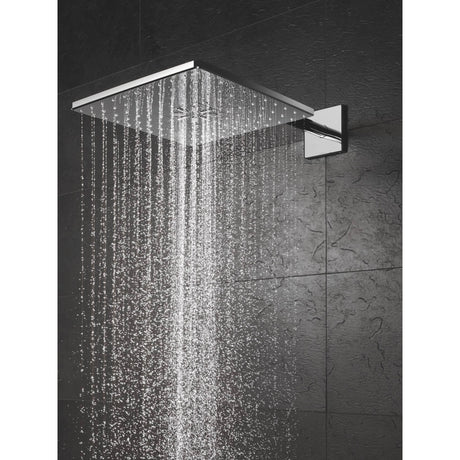 Pommeau de douche Grohe, modèle carré, couleur chromée, effet pluie sur mur noir.