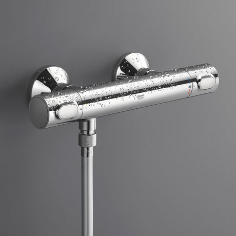 Mitigeur thermostatique de douche Grohe en finition chromée, installé sur un mur gris.