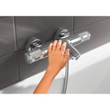 Mitigeur de baignoire Grohe chromé, main réglant le robinet, couleur argentée