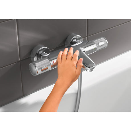 Mitigeur de baignoire Grohe chromé, main réglant le robinet, couleur argentée
