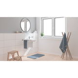 Tapis de bain bleu Grohe pour salle de bain moderne, posé devant un lavabo blanc.