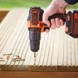 Perceuse visseuse noire et orange Black+Decker en action sur bois, outil électroportatif.