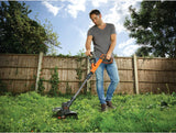 Coupe-bordures Black & Decker orange utilisé dans un jardin, outil de jardinage électrique