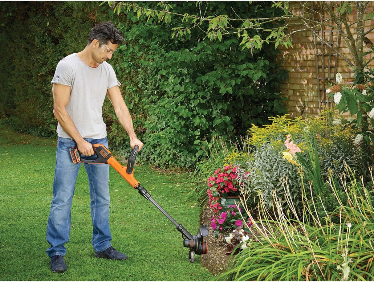 Homme utilisant un coupe-bordure Black+Decker orange pour jardinage sur pelouse