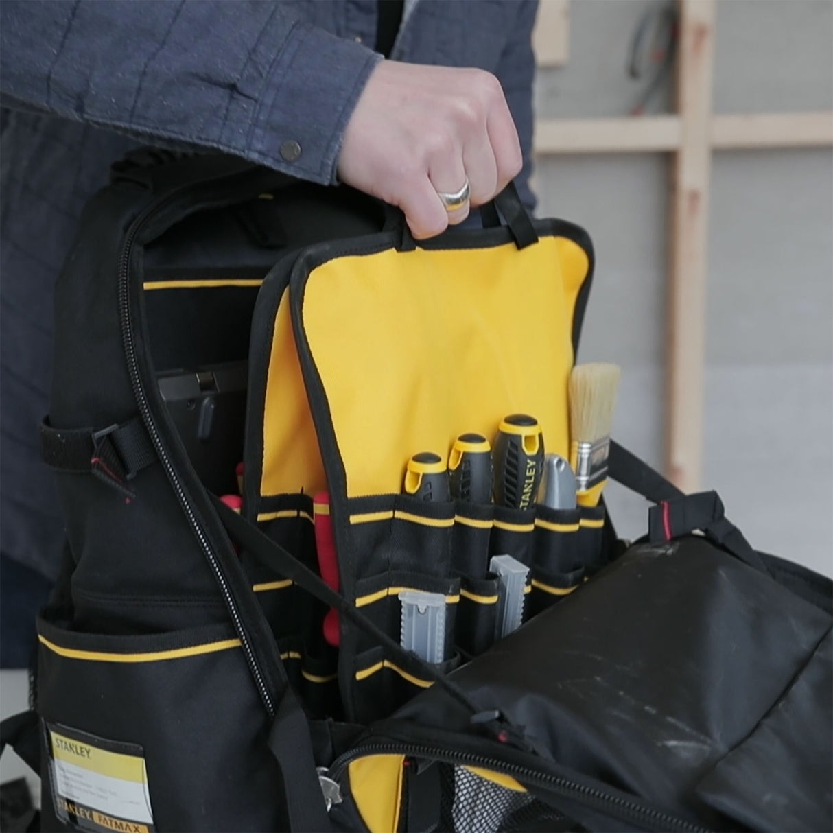 Sac à outils Stanley noir et jaune, avec outils visibles, type sac à dos professionnel.