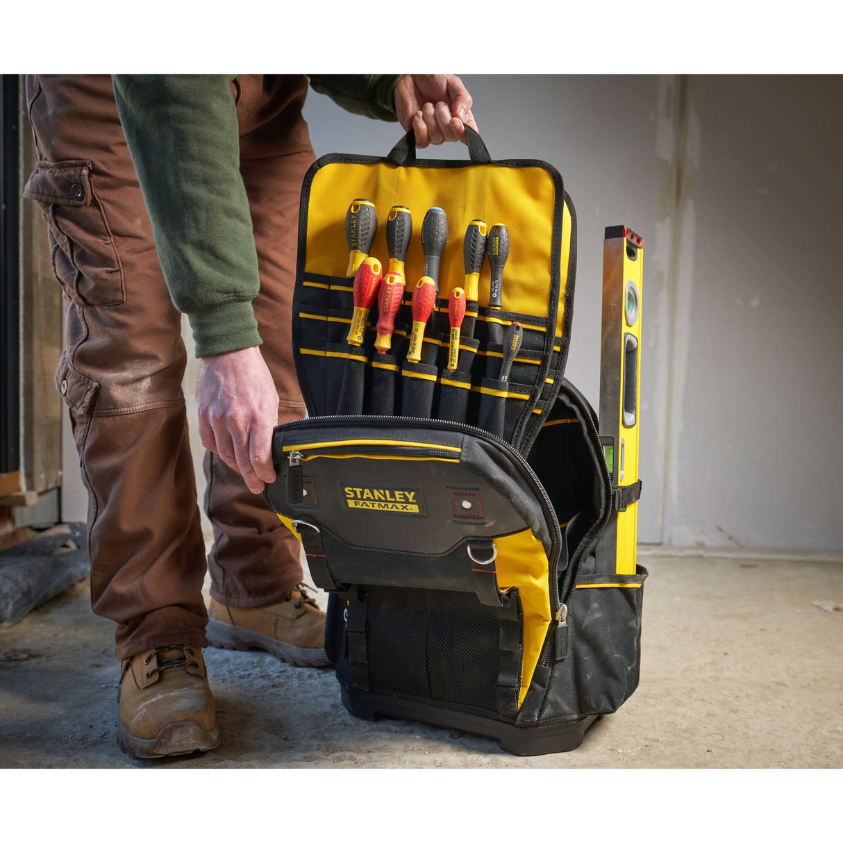 Sac à outils Stanley FATMAX jaune et noir, type sac à dos, avec outils visibles.