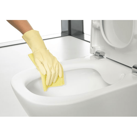 Nettoyage d'une cuvette de WC blanc Roca avec gant jaune, toilette céramique blanche.