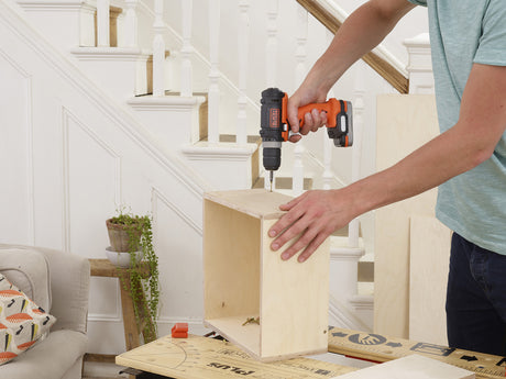Perceuse sans fil Black+Decker, outil électroportatif, couleur orange et noire, en usage sur bois.
