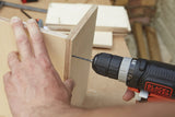 Perceuse électrique Black+Decker noire et orange, outil électroportatif en action sur bois clair