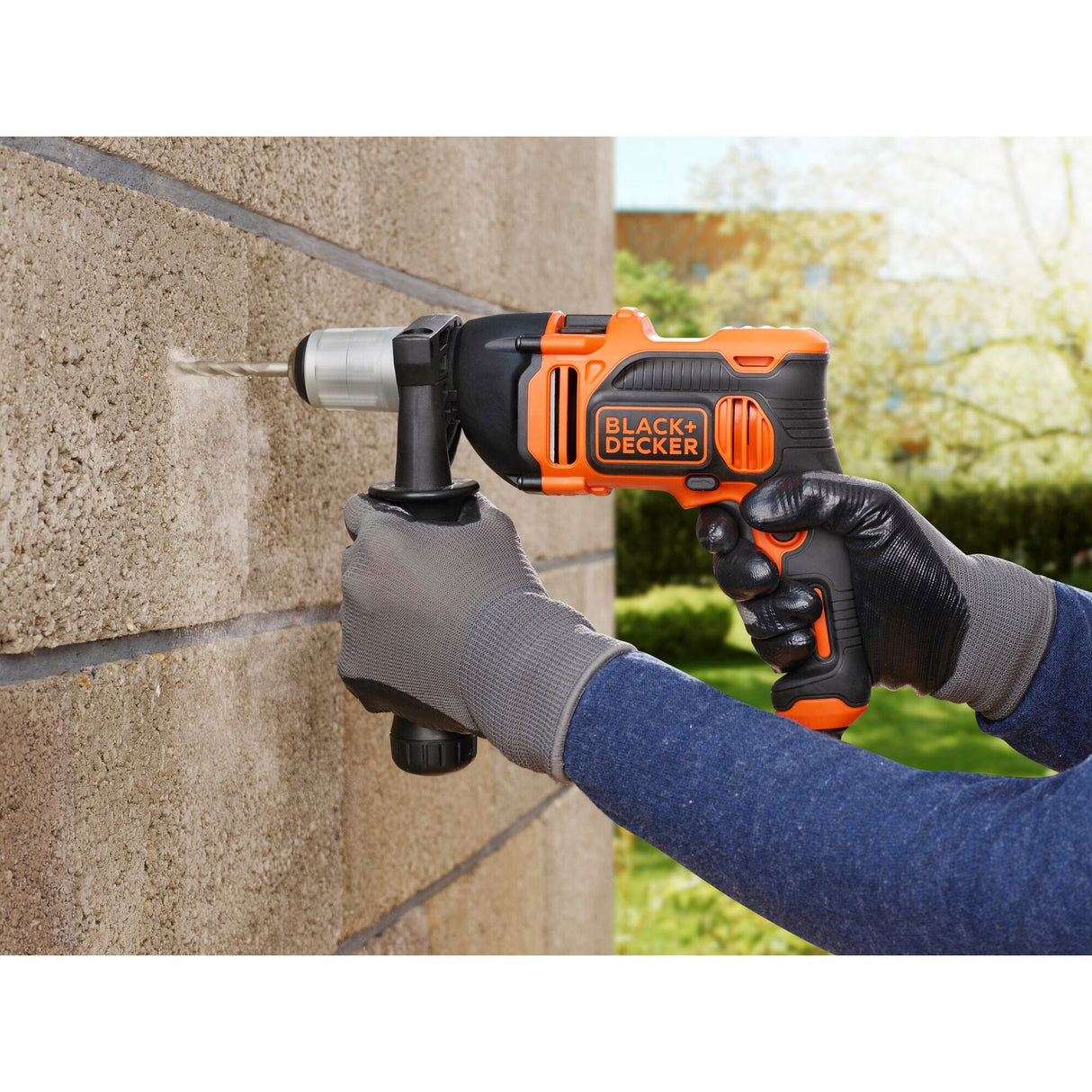 Perceuse BLACK+DECKER orange et noire, outil électroportatif, utilisée sur mur en béton