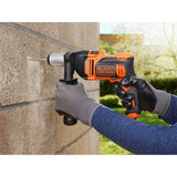 Perceuse BLACK+DECKER orange et noire, outil électroportatif, utilisée sur mur en béton