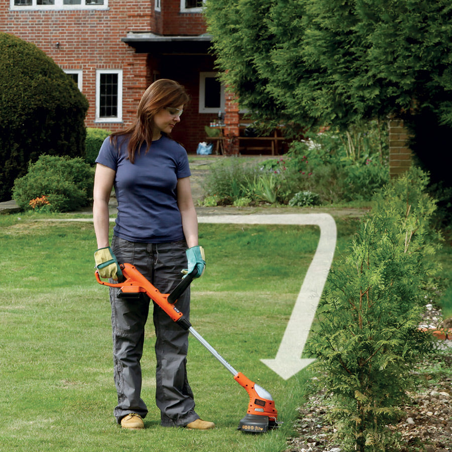 Coupe-bordures Black+Decker, outil de jardinage orange, utilisé sur pelouse verte.