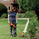 Coupe-bordures Black+Decker, outil de jardinage orange, utilisé sur pelouse verte.