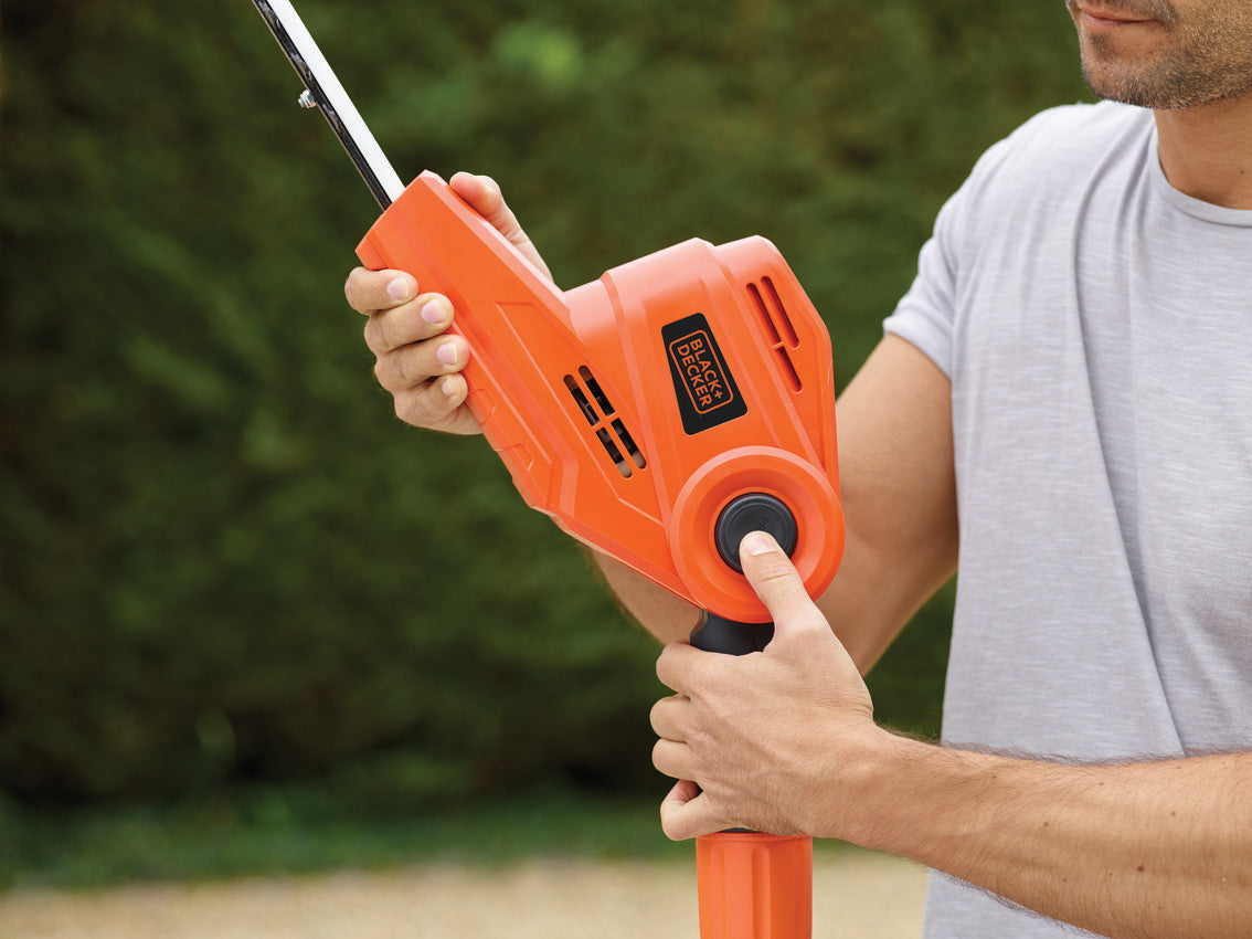 Taille-haie Black+Decker orange électrique, outil de jardinage en main, couleur orange.