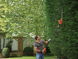 Taille-haie télescopique Black+Decker orange utilisé pour tailler une haie verte