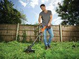 Débroussailleuse orange Black & Decker, outil de jardinage, utilisée sur de l’herbe verte