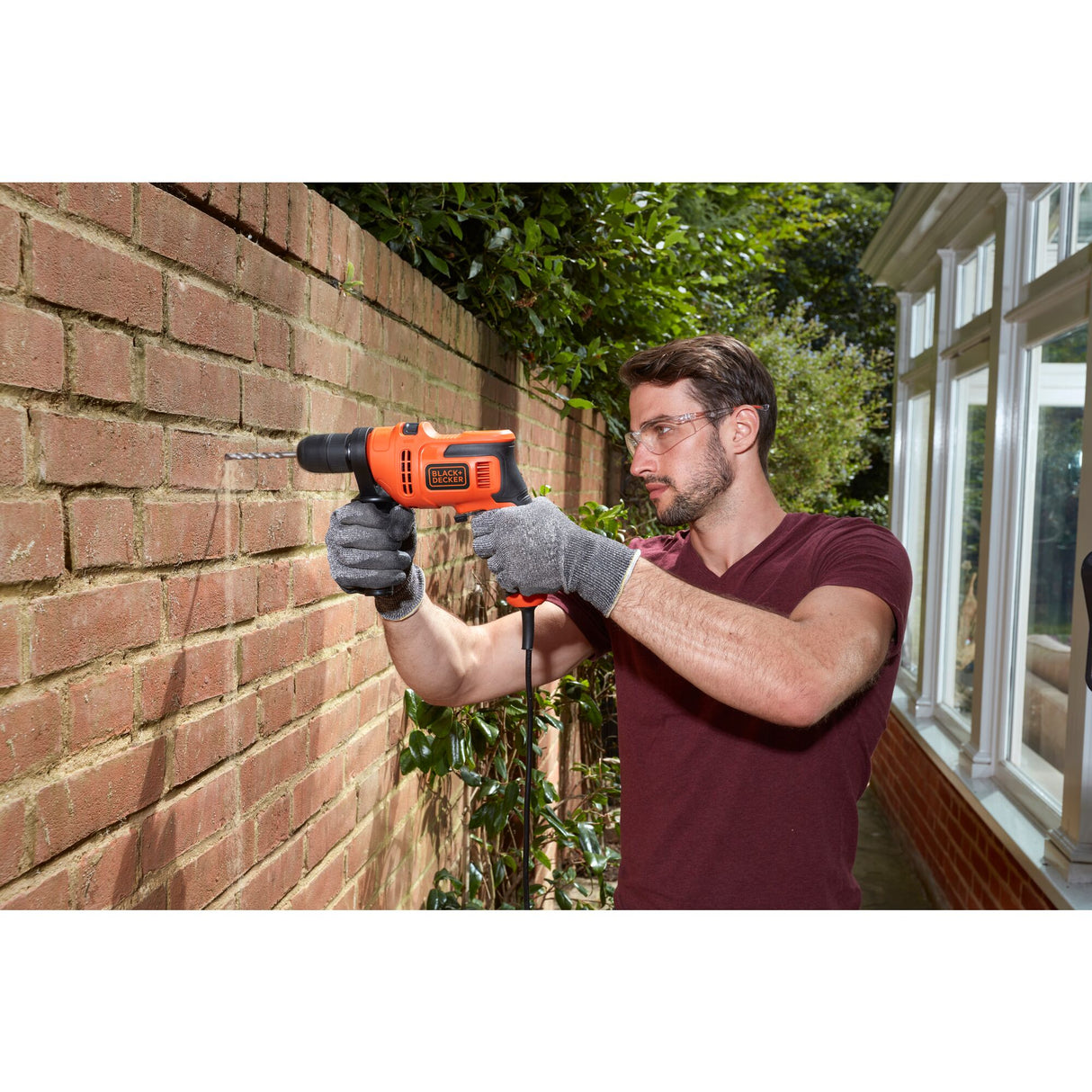 Perceuse électrique Black+Decker orange, outil de bricolage utilisé sur un mur en brique