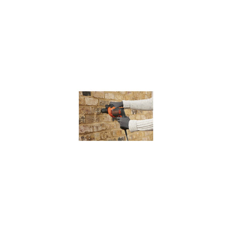 Perceuse Black+Decker, outil électroportatif, couleur orange et noire, utilisée sur un mur en brique