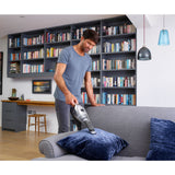 Aspirateur à main Black+Decker, gris, utilisé sur un canapé dans un salon moderne