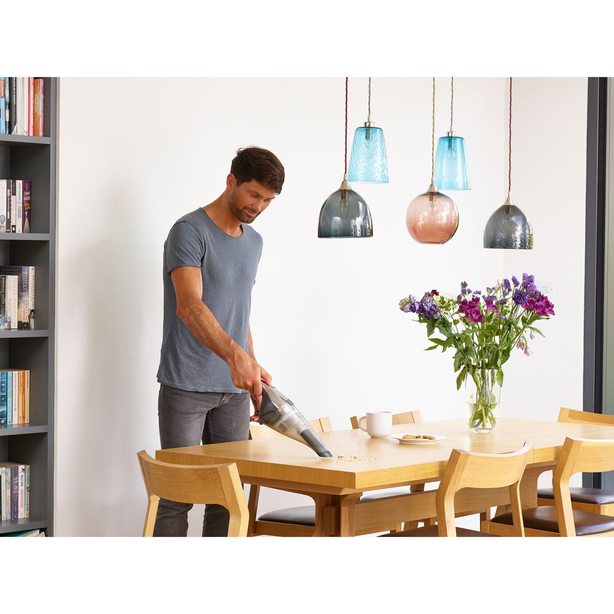 Aspirateur à main Black+Decker, gris, utilisé pour nettoyer une table en bois.