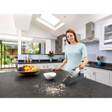 Aspirateur à main Black+Decker, noir, utilisé dans une cuisine moderne pour nettoyer un plan de travail.