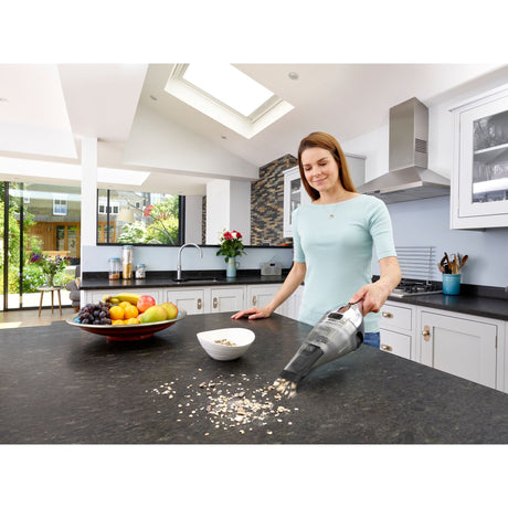 Aspirateur à main Black+Decker, noir, utilisé dans une cuisine moderne pour nettoyer un plan de travail.