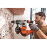 Perforateur burineur Black+Decker orange et gris utilisé sur un mur en briques