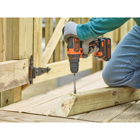 Perceuse-visseuse sans fil Black+Decker noire et orange utilisée sur du bois