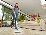 Balai vapeur Vileda blanc et bleu utilisé pour nettoyer un tapis dans un salon lumineux