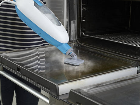 Nettoyeur vapeur Black+Decker, type balai vapeur, couleur blanc et bleu, utilisé pour nettoyer la porte d’un four.