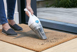 Aspirateur à main Black+Decker, blanc et gris, utilisé pour nettoyer un paillasson.