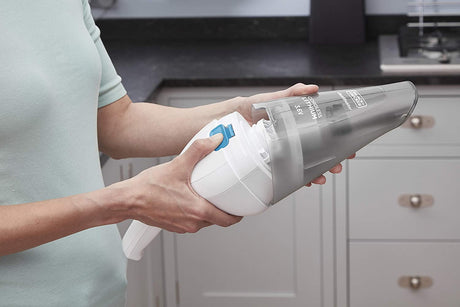 Aspirateur à main Black+Decker, gris et blanc, en utilisation dans une cuisine