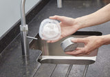 Filtre de remplacement Quooker, accessoire sanitaire, couleur gris clair, présenté au-dessus d’un évier moderne.